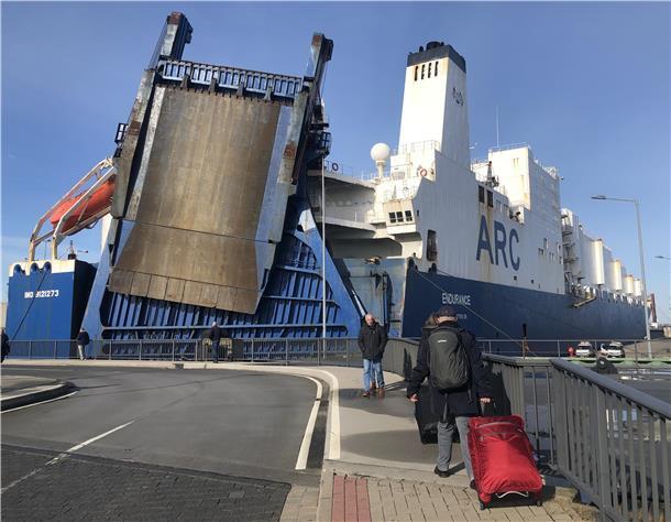 Zwei Welten: Vorne Kreuzfahrt-Passagiere auf dem Weg zur "Mein Schiff 3", im Hintergrund das Transportschiff mit den Militärgütern.