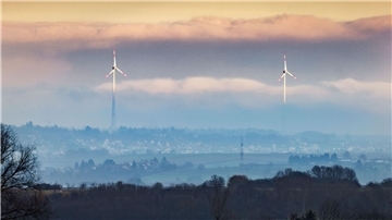 Zwei Windräder ragen aus dem Dunst über der Wetterau heraus.