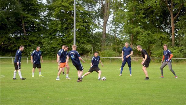 Männer mit blauen Shirts auf einem Fußballplatz beim Training.