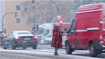 Zwischen wartenden Autos an der Ampfel: Bitten um Almosen bei Schneetreiben in Hamburg.
